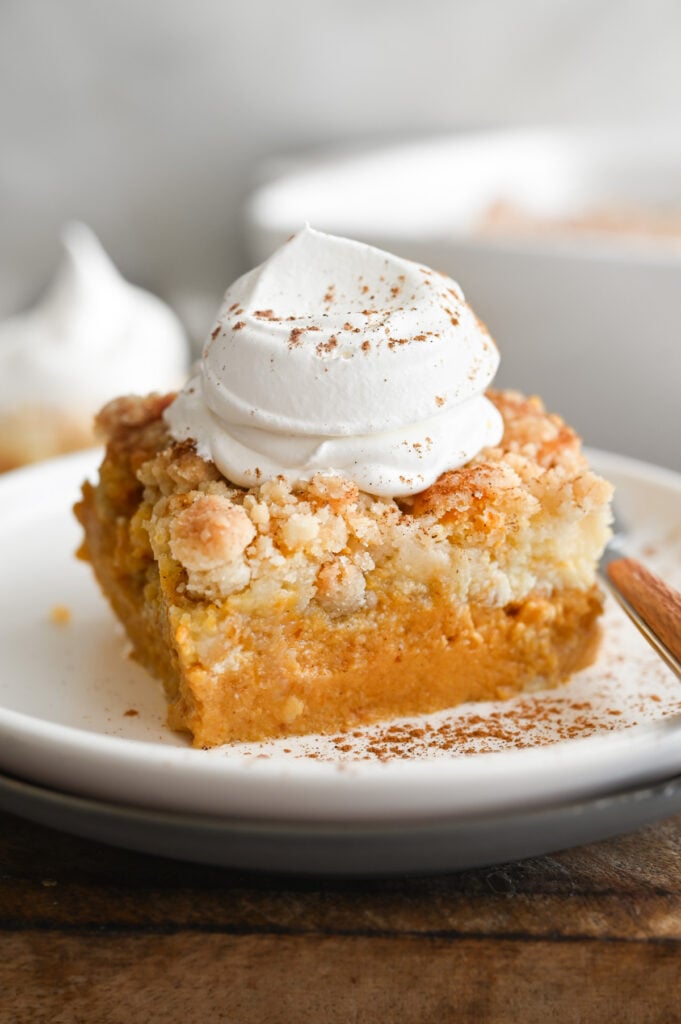 A square piece of pumpkin cream cheese dump cake on a white plate.
