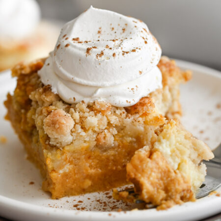 A scoop of pumpkin dump cake with cream cheese and a dollop of whipped topping on top.