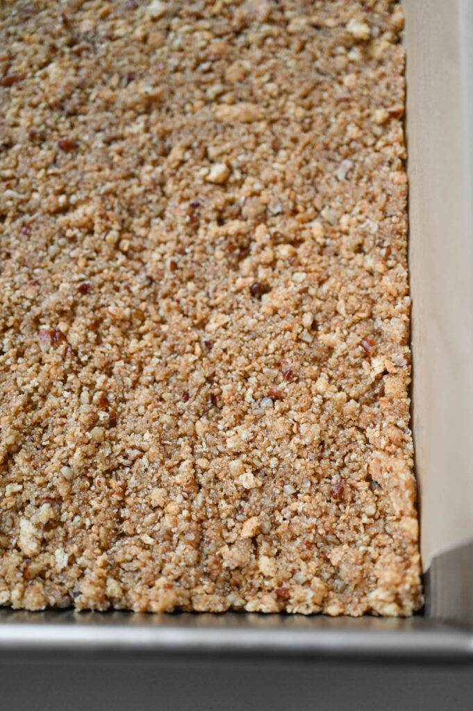 Unbaked pecan graham cracker crust in a metal baking pan.