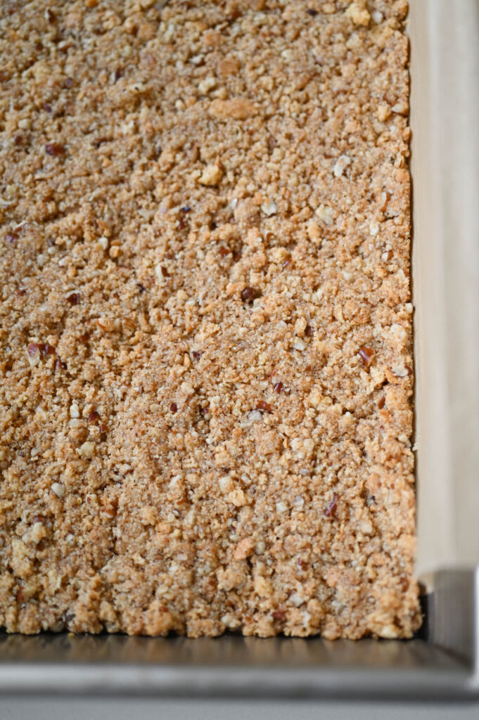 Baked pecan graham cracker crust in a metal baking pan.