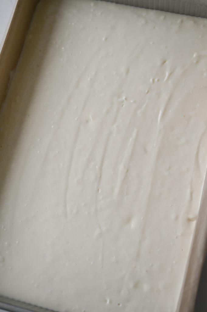 Cheesecake filling in a 9x13-inch pan ready to be baked.