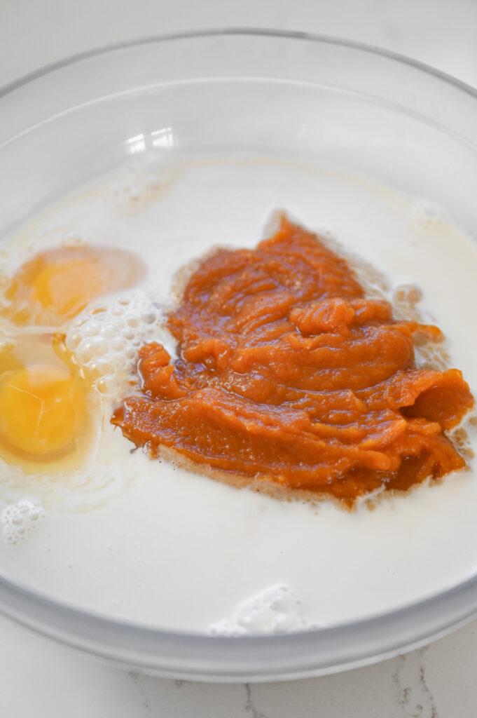 Pumpkin filling, eggs and milk in a bowl.