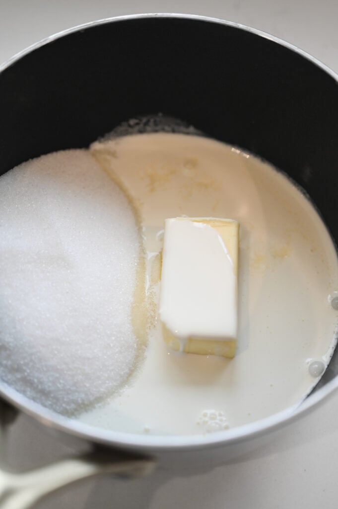 A saucepan with sugar, butter, and heavy cream in it.
