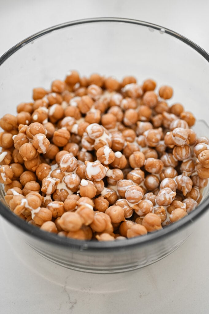 A glass container with caramel bits and heavy cream in it.