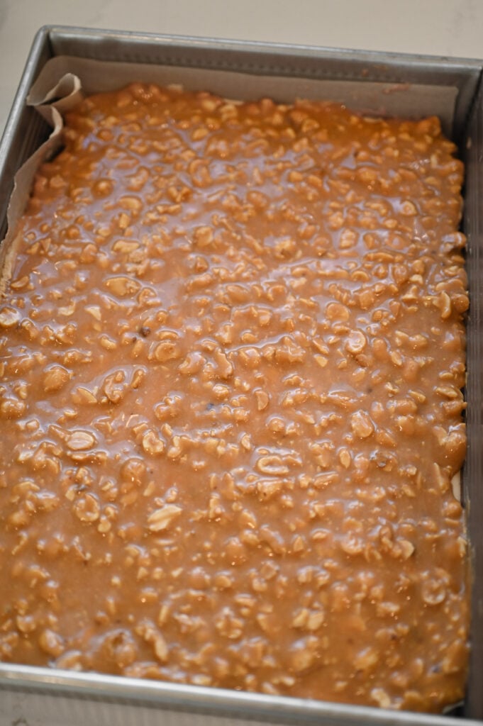 Peanut-caramel mixture spread on top of a 9x13-inch pan of bars.