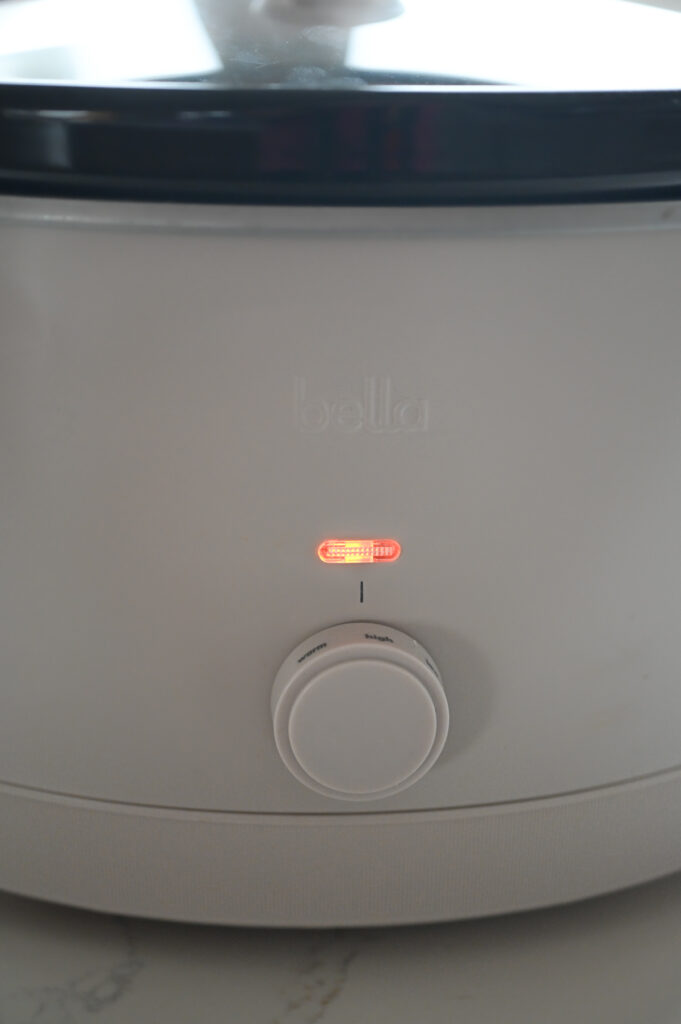 The front of a slow cooker with the light on showing that it's on "high."