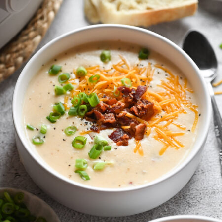 A bowl of potato soup with bacon, cheese, and green onions.