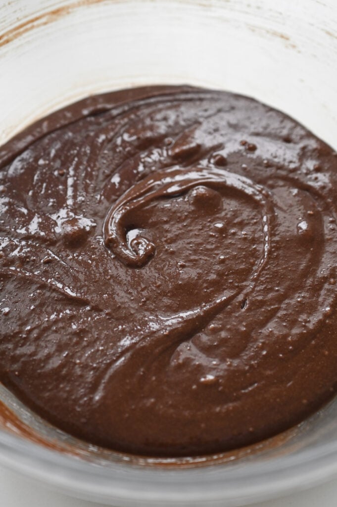 Brownie batter in a clear glass bowl.