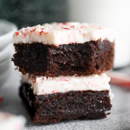 Two peppermint bark brownies stacked on each other; the top one has a bite out of it.