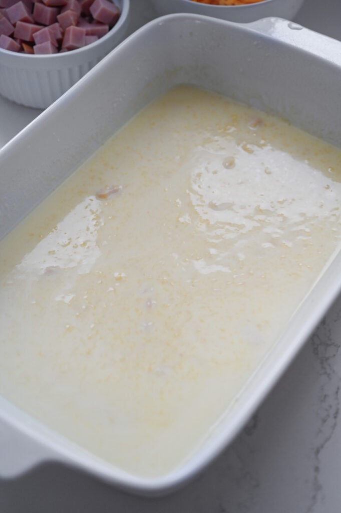 Milk and cream of chicken soup mixed in a white ceramic baking dish.