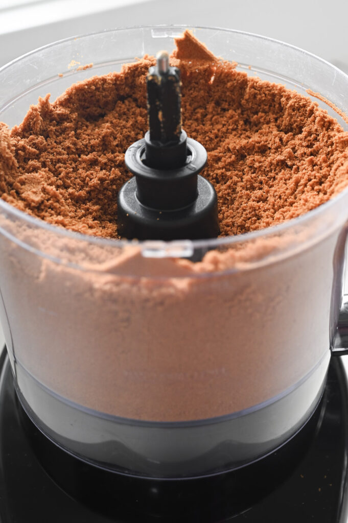 Pulverized Biscoff cookies in the base of a food processor.