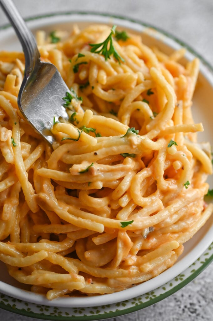 A fork grabbing a bite of a creamy spaghetti dish.