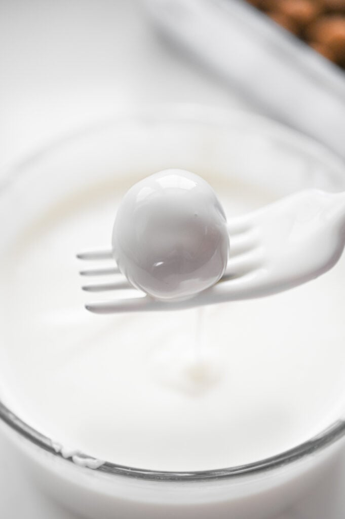 A truffle dipped in white chocolate with a fork.
