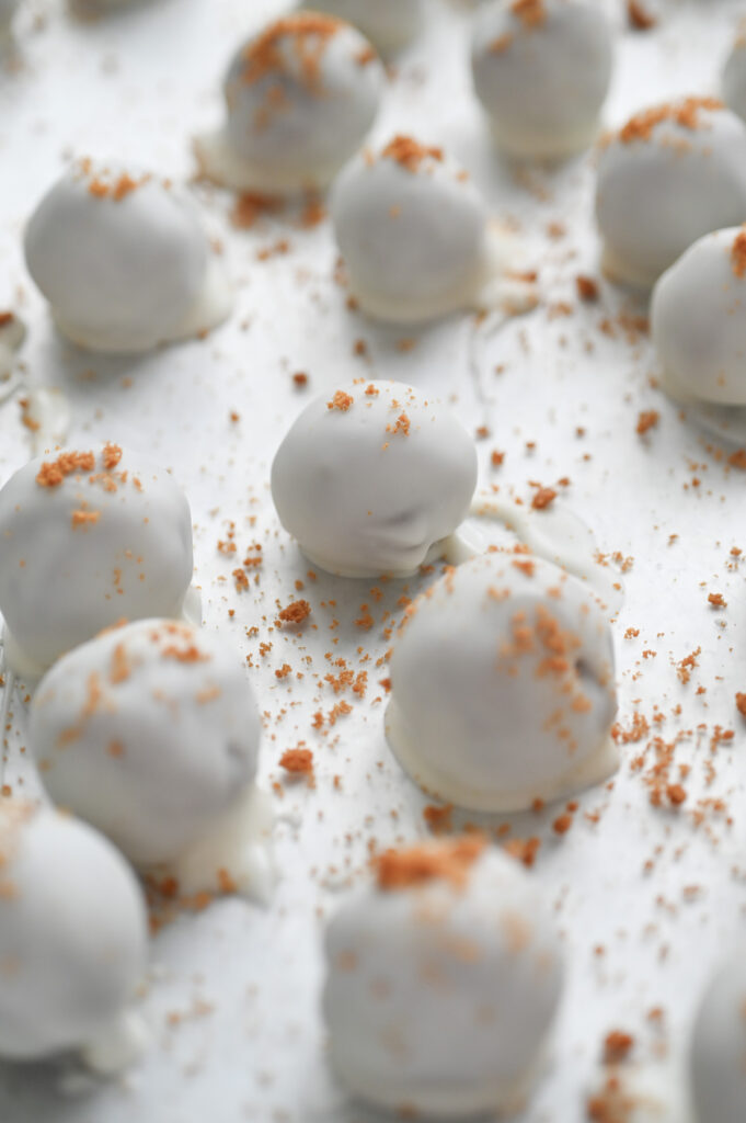 Almond bark coated Biscoff truffles on a waxed paper lined baking sheet.