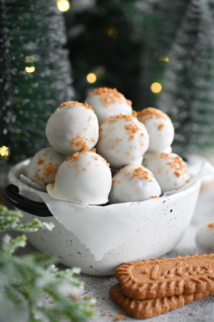 Several truffles coated in white chocolate with Biscoff cookie crumbs on top.