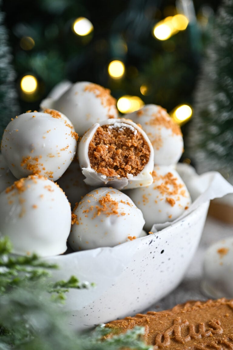 A bowl of Biscoff Truffles; one in the middle has a bite out of it showing the brown interior.