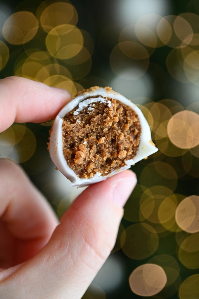 A hand holding a Biscoff truffle with a bite out of it.