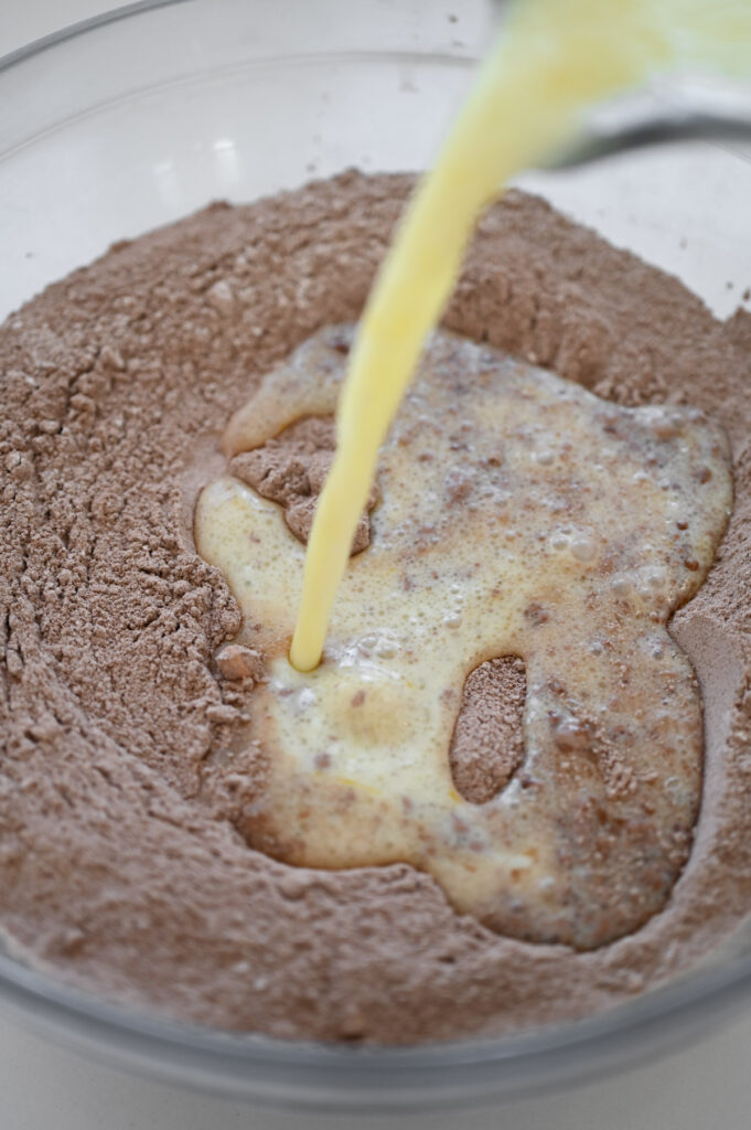 Pouring wet ingredients into a bowl of dry ingredients.