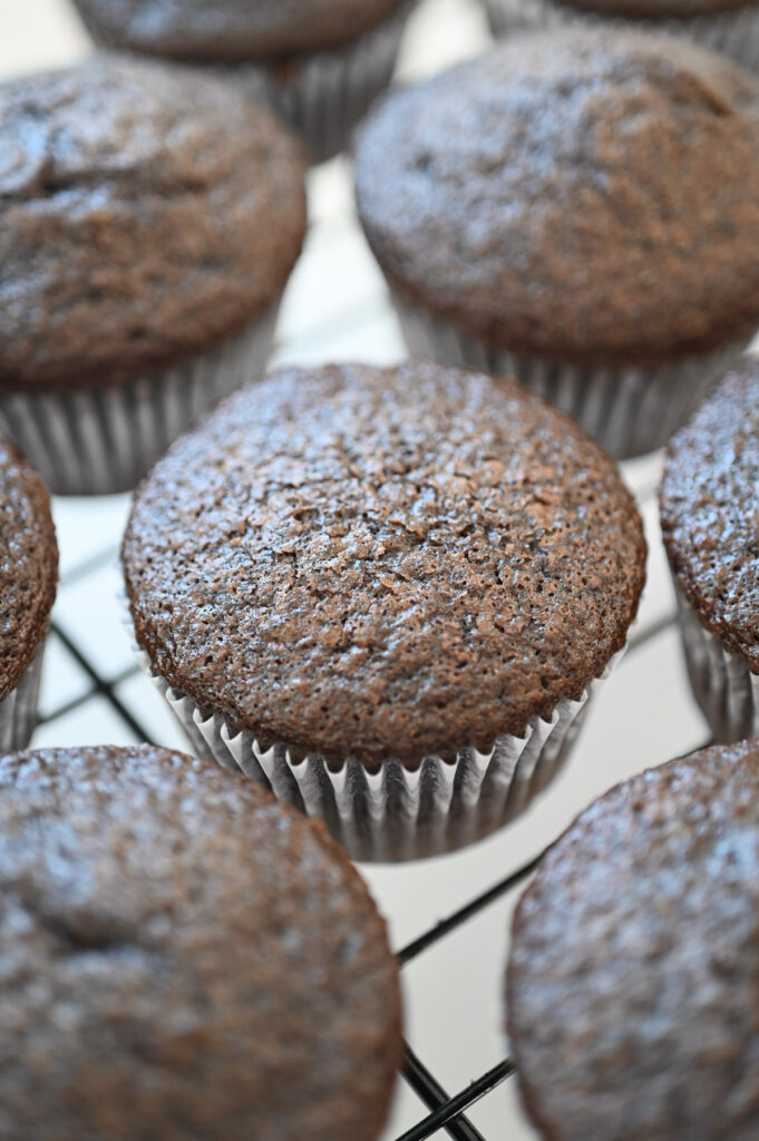 Baked chocolate cupcakes on a wire rack.