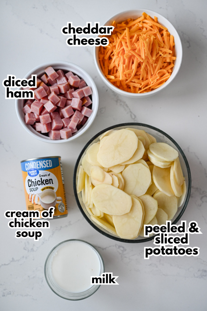 The five ingredients needed to make an easy cheesy scalloped potatoes and ham on a white marble background.