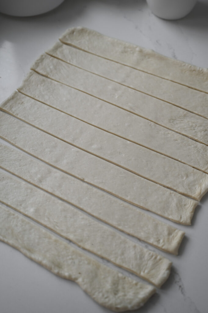 A sheet of dough cut into 9 even strips.