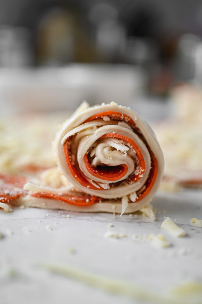 A pepperoni roll being rolled up.