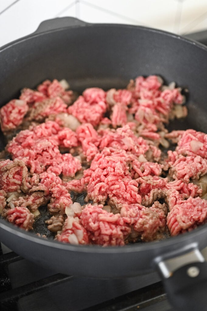 Raw ground beef being sautéed in a skillet.