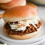 A bbq sloppy Joe on a white plate. This one has bbq sloppy Joe meat and coleslaw!