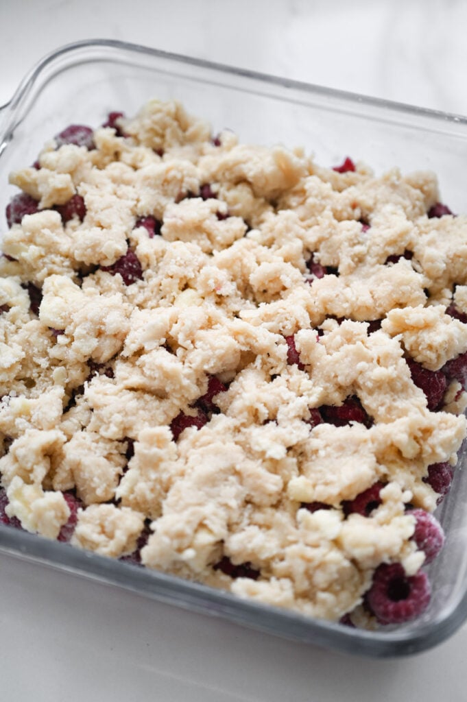 A cobbler topping covering the raspberries in a square dish.