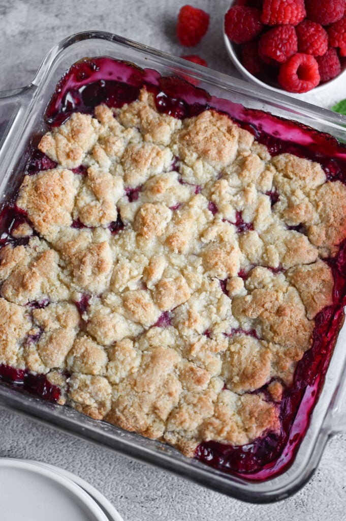 A baked cobbler with berries on the side.