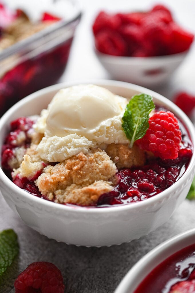 A bowl of raspberry cobbler with a scoop of ice cream on top.