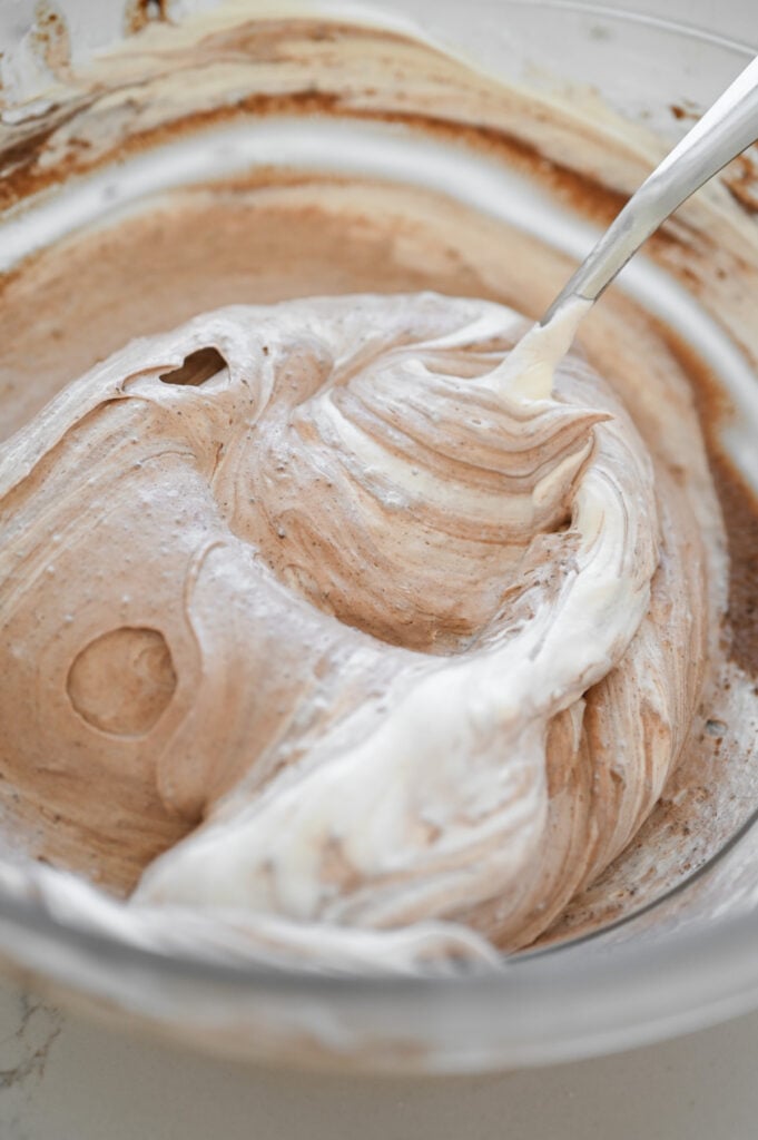 A spoon stirring whipped topping and chocolate.