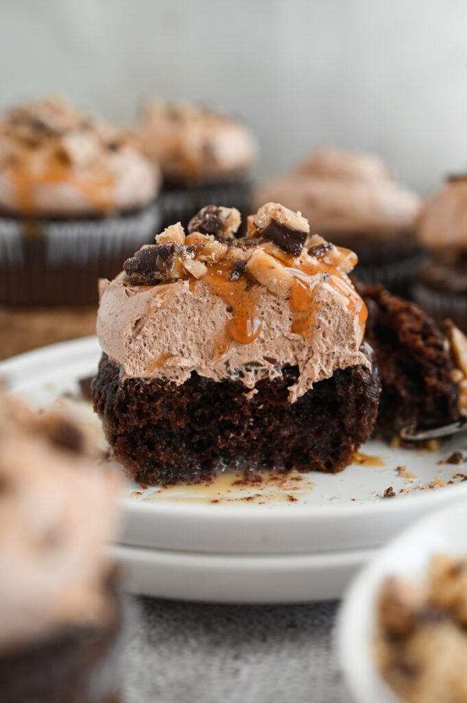 A better than anything cupcake with a bite out of it on a wooden board.