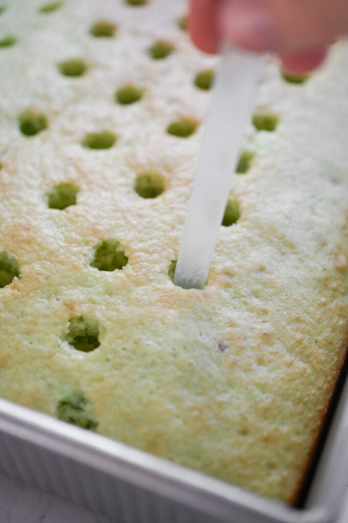 A straw poking holes into a cake.