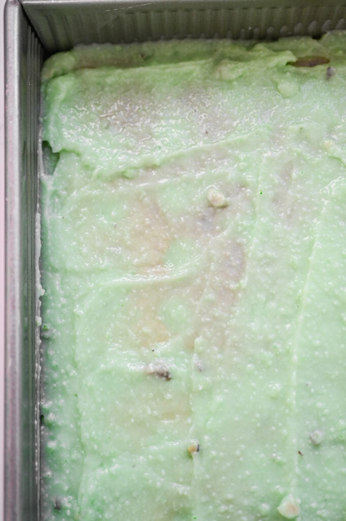 A green pistachio pudding spread overtop of a cake.