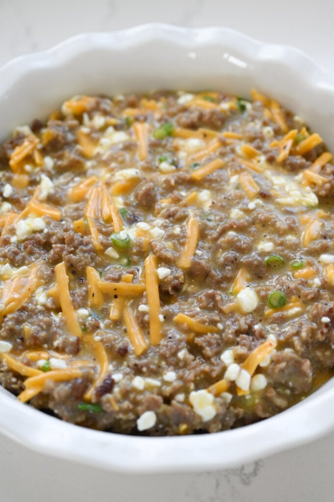 The filling of a breakfast tater tot casserole in a pie plate.