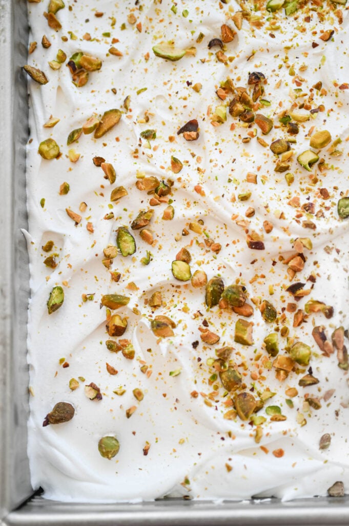 A cake with whipped cream and pistachios on top.