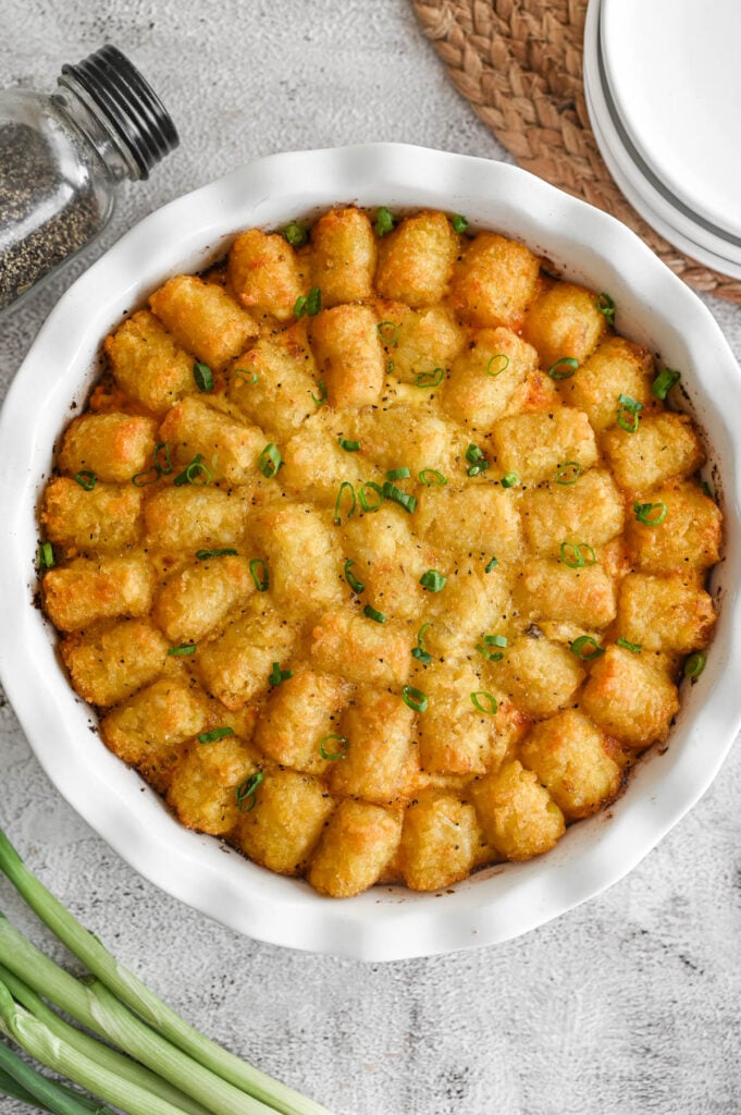 Overhead view of a breakfast tater tot casserole in a white ceramic pie plate.