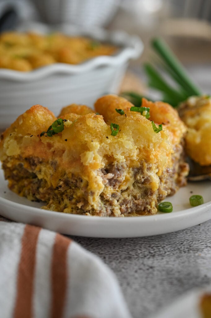 A plate with a breakfast casserole on it; a bite is out of the casserole.