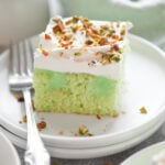 A square piece of pistachio poke cake on a white plate.