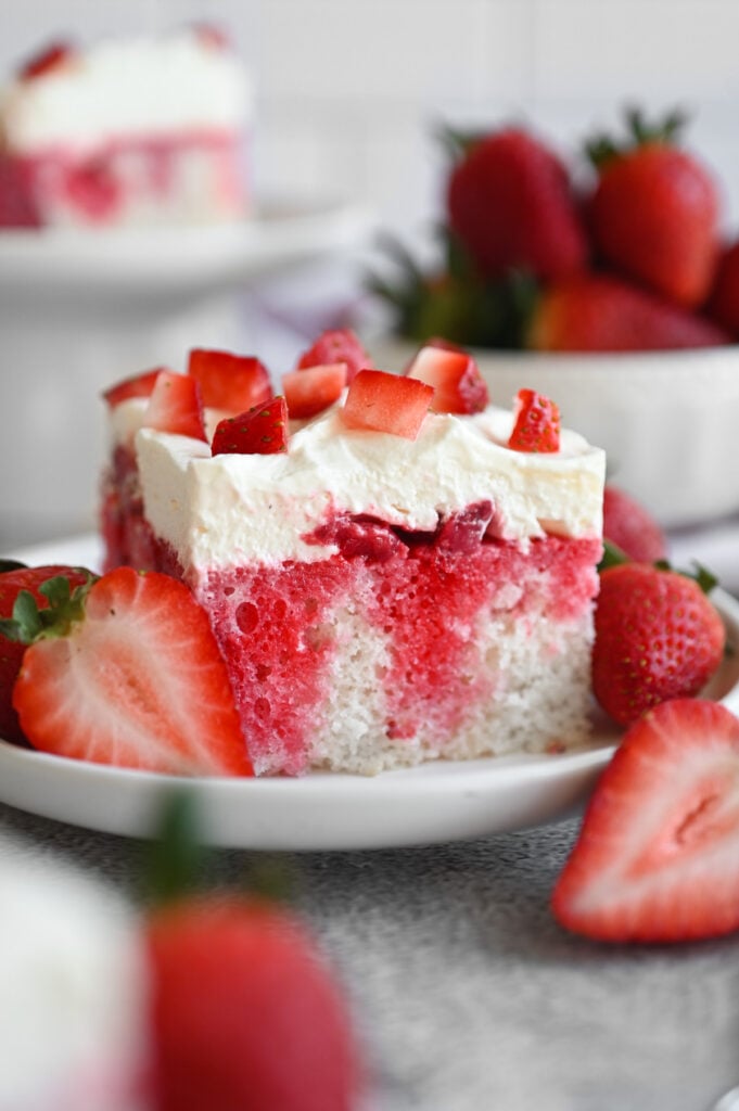 Berries and cream poke cake recipe on a white plate.