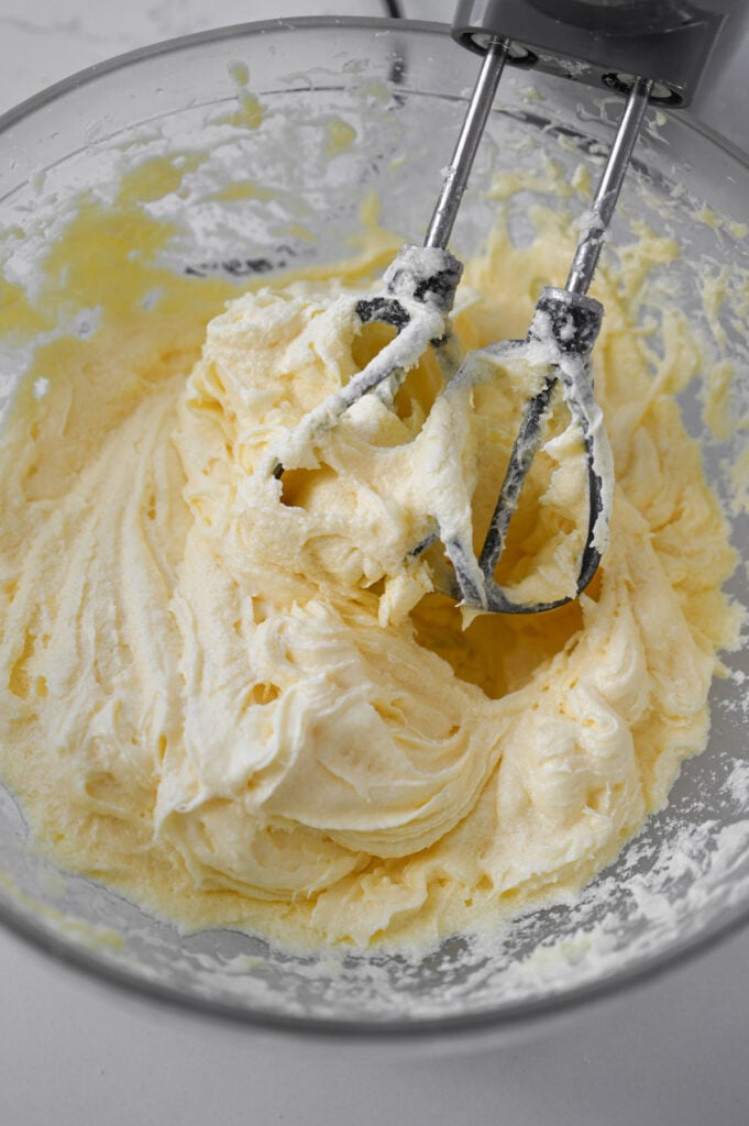An electric hand mixer creaming butter and sugar.