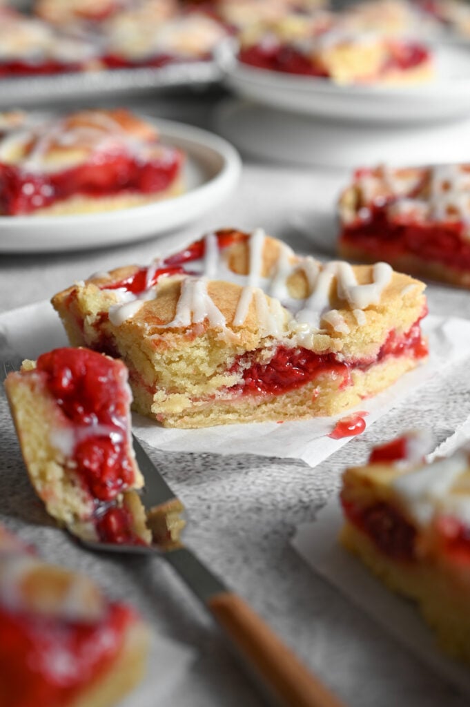 A close-up of a cherry pie bar with a forkful out of it.
