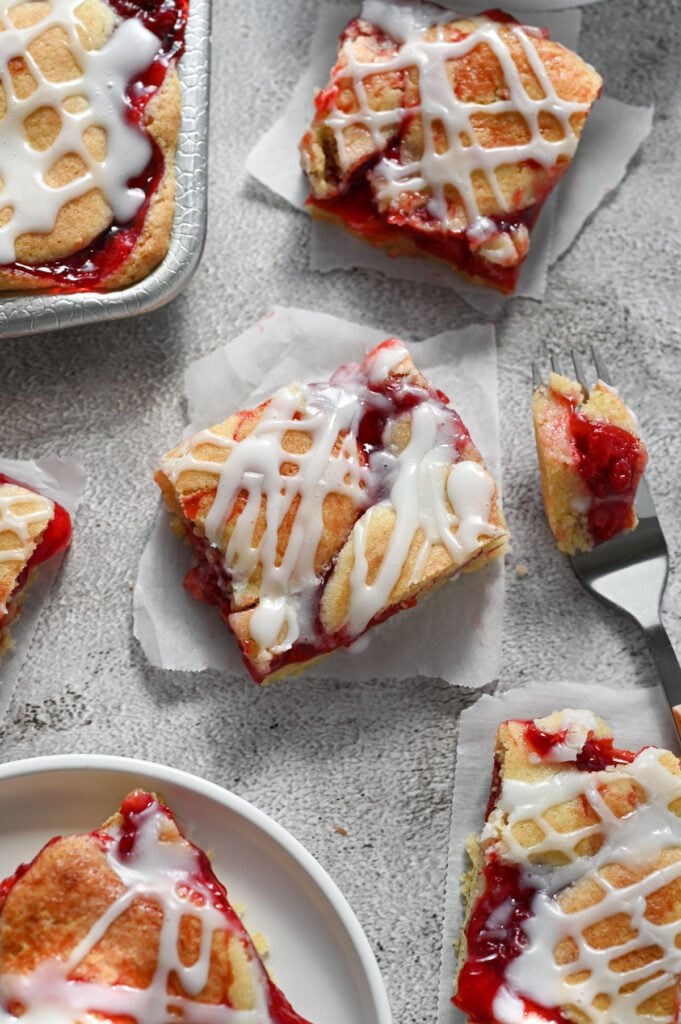 Several slices of old fashioned cherry pie bars on a gray-ish background.
