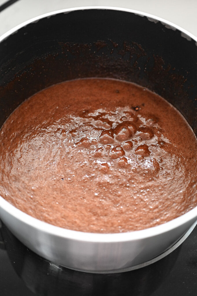 A chocolate mixture in a saucepan boiling.