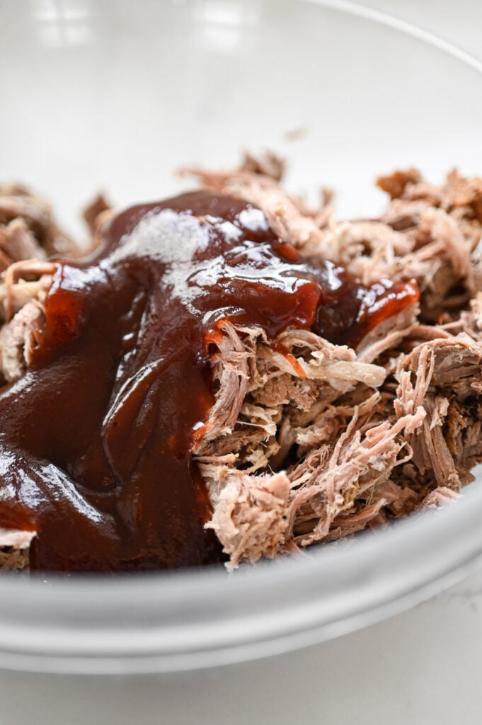 Barbecue sauce and pulled pork in a glass bowl.