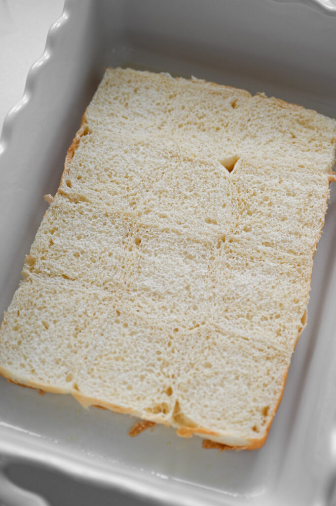 The bottoms of a sheet of Hawaiian Rolls in a white ceramic 9x13-inch pan.