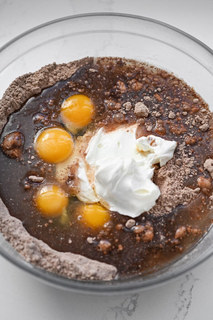 The ingredients to make a chocolate cake in a glass bowl.