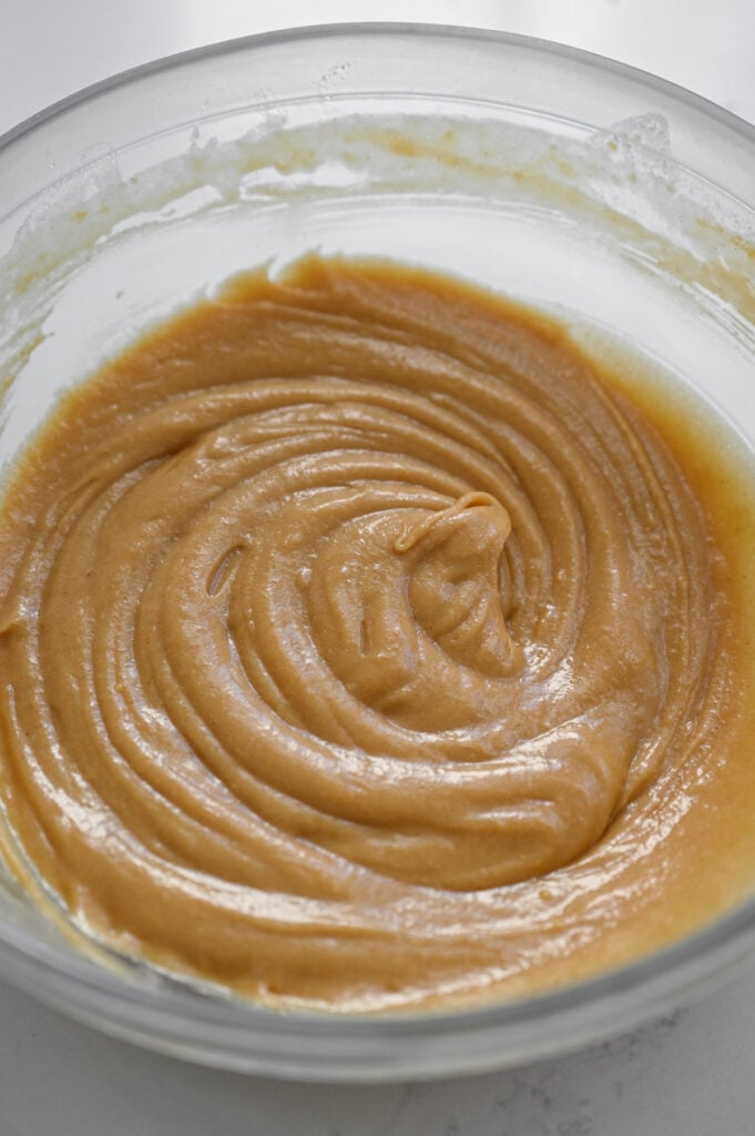 A smooth peanut butter batter in a clear glass bowl.