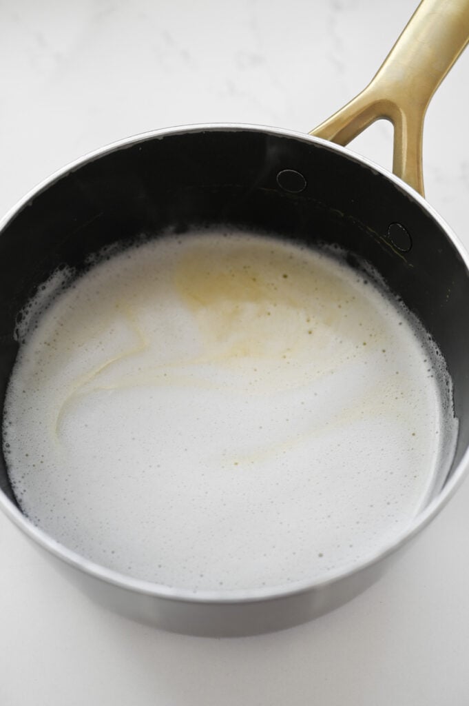 A liquid with a little bit of foam in a saucepan.